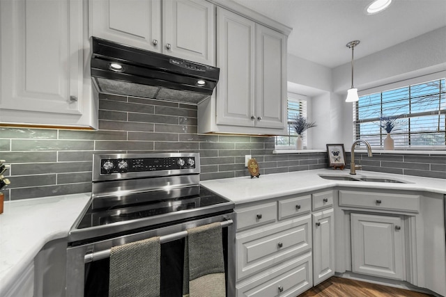 kitchen with under cabinet range hood, electric range, tasteful backsplash, and a sink