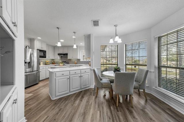 dining room with visible vents, a textured ceiling, wood finished floors, recessed lighting, and a chandelier