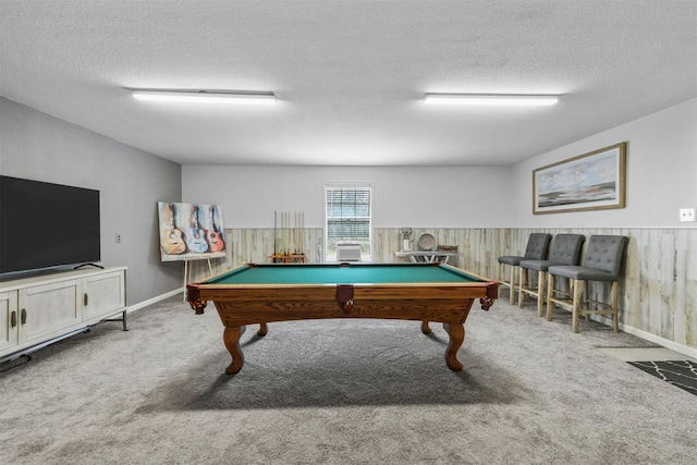 rec room featuring a wainscoted wall, a textured ceiling, wood walls, and carpet flooring