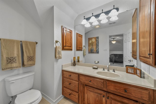 bathroom with visible vents, toilet, baseboards, vanity, and vaulted ceiling