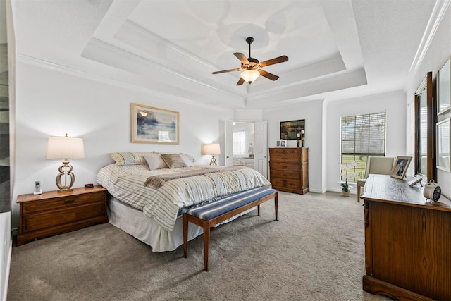 carpeted bedroom with a tray ceiling, baseboards, and ornamental molding