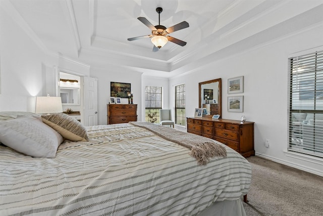 carpeted bedroom featuring a tray ceiling, ornamental molding, and a ceiling fan