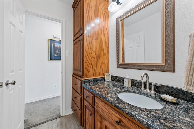 bathroom featuring vanity, baseboards, and wood finished floors