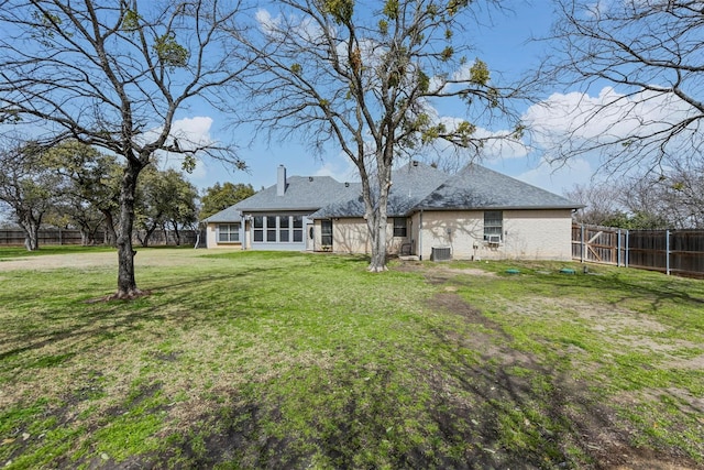 back of house with brick siding, fence, a lawn, a chimney, and a sunroom