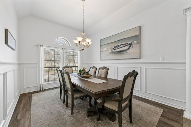 dining room featuring a wainscoted wall, an inviting chandelier, a decorative wall, lofted ceiling, and dark wood-style flooring