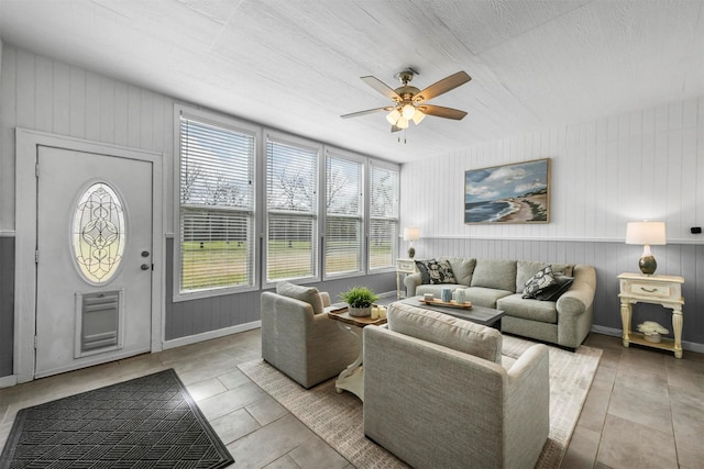 living area with baseboards and a ceiling fan