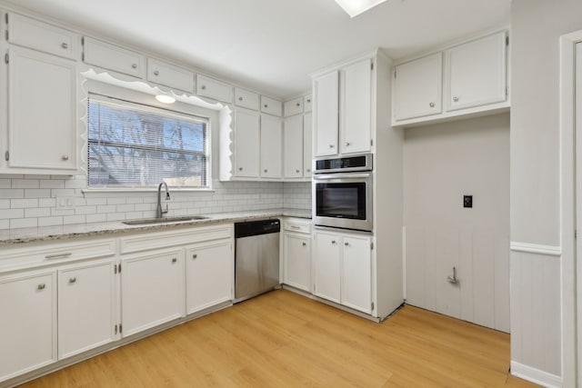 kitchen featuring white cabinets, light wood-style floors, appliances with stainless steel finishes, and a sink