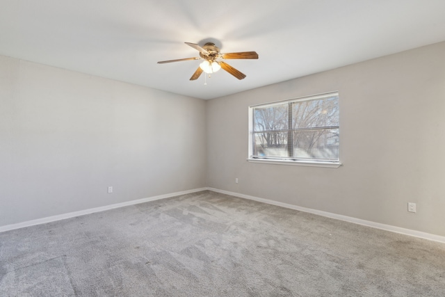 carpeted spare room featuring baseboards and ceiling fan