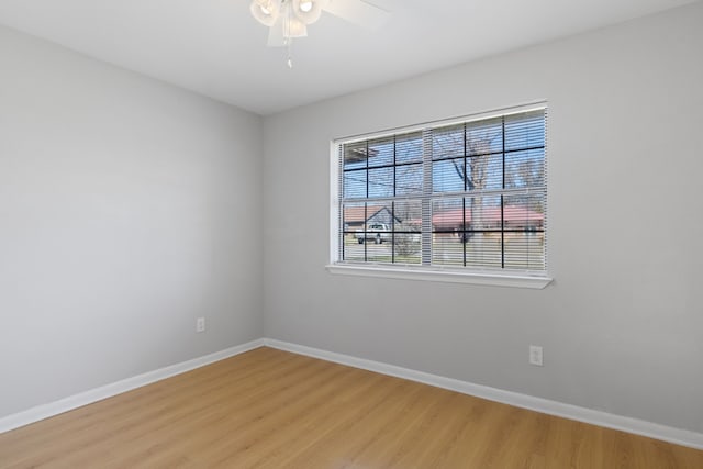 spare room featuring light wood-style flooring, a ceiling fan, and baseboards