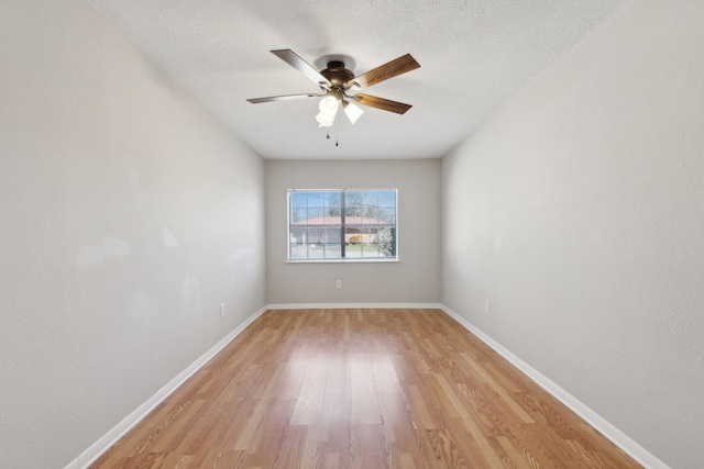 unfurnished room with ceiling fan, baseboards, a textured ceiling, and light wood-style flooring