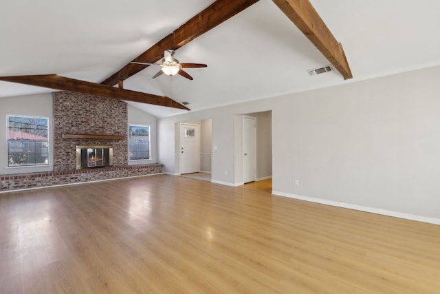 unfurnished living room featuring visible vents, a brick fireplace, a healthy amount of sunlight, and a ceiling fan