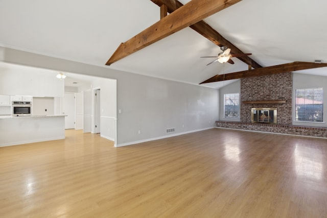 unfurnished living room with ceiling fan, a fireplace, visible vents, and a healthy amount of sunlight