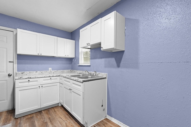 laundry room featuring dark wood-style floors, a textured wall, and a sink