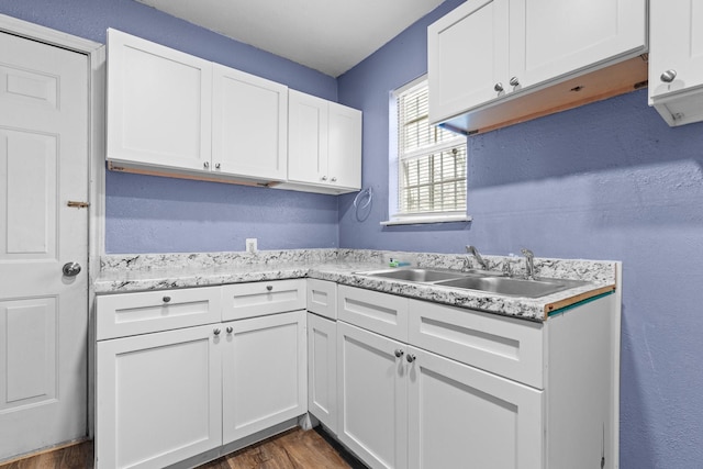 kitchen featuring a sink, dark wood-type flooring, white cabinets, and light countertops