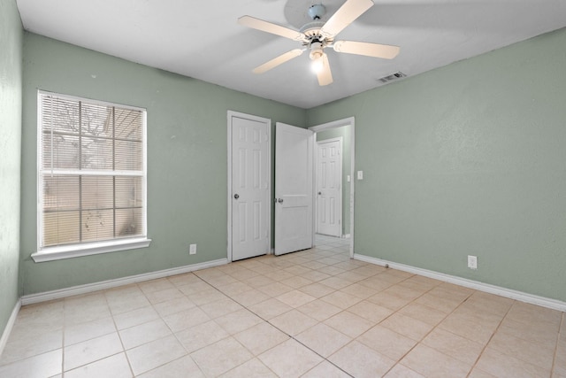 empty room with a wealth of natural light, visible vents, baseboards, and ceiling fan