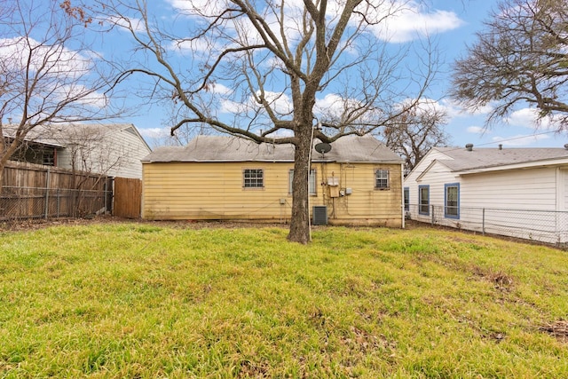 rear view of property featuring a yard, central AC unit, and a fenced backyard