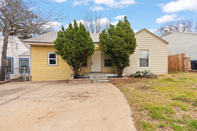 view of front of home featuring fence, driveway, and a shingled roof