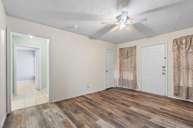 empty room with wood finished floors, baseboards, and ceiling fan