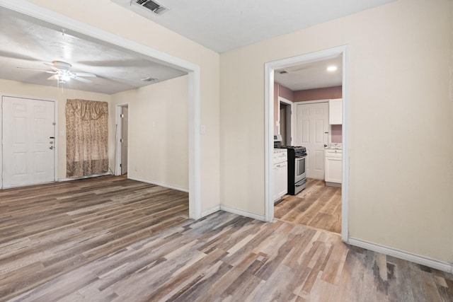 spare room with visible vents, ceiling fan, light wood-type flooring, and baseboards