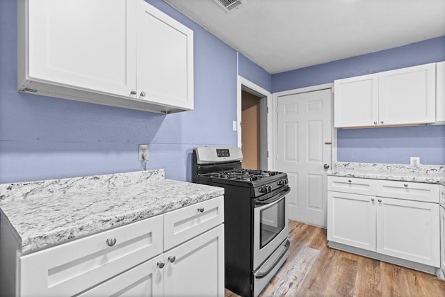 kitchen featuring white cabinets, gas stove, light wood-style flooring, and light stone countertops