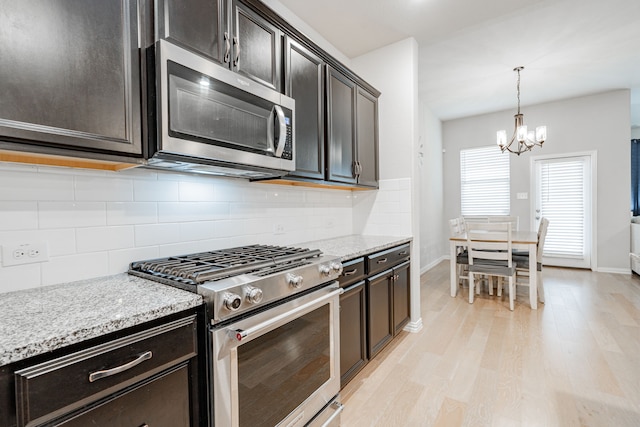 kitchen with decorative backsplash, light wood finished floors, light stone countertops, and appliances with stainless steel finishes