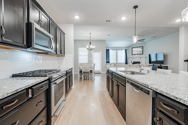 kitchen featuring visible vents, a sink, tasteful backsplash, light wood-style floors, and appliances with stainless steel finishes