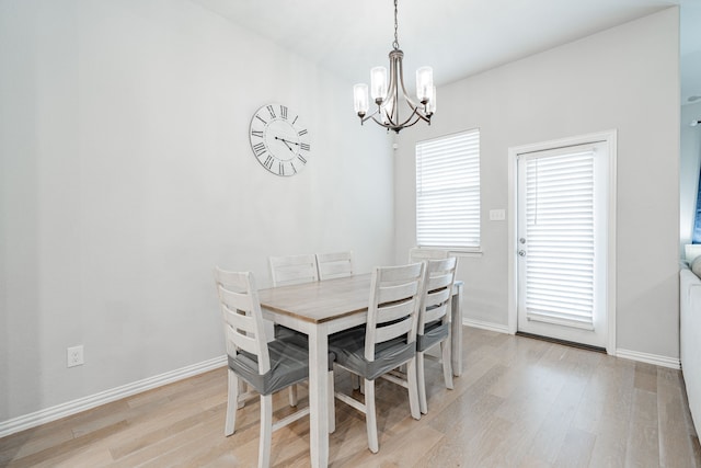 dining space featuring light wood-type flooring, baseboards, and a notable chandelier