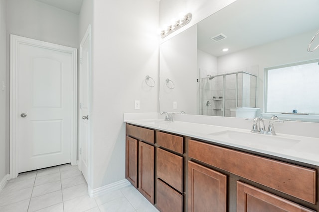 bathroom with tile patterned floors, double vanity, a stall shower, and a sink