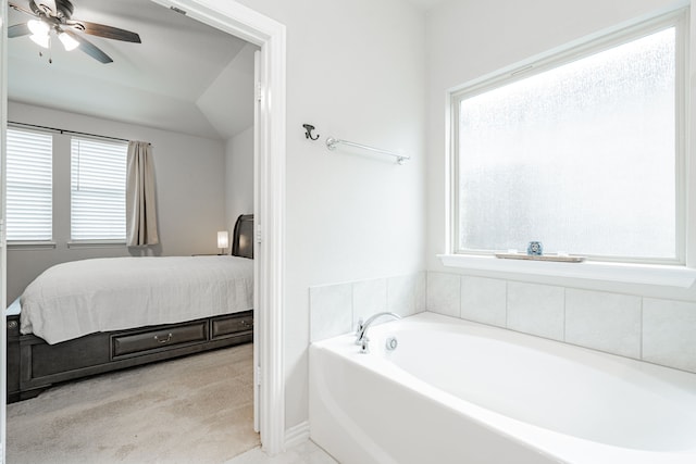 ensuite bathroom with ceiling fan, connected bathroom, plenty of natural light, and a bath