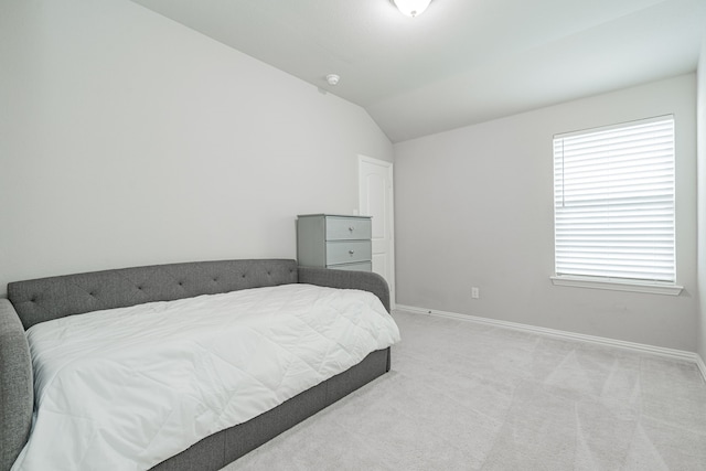 bedroom with lofted ceiling, light colored carpet, and baseboards