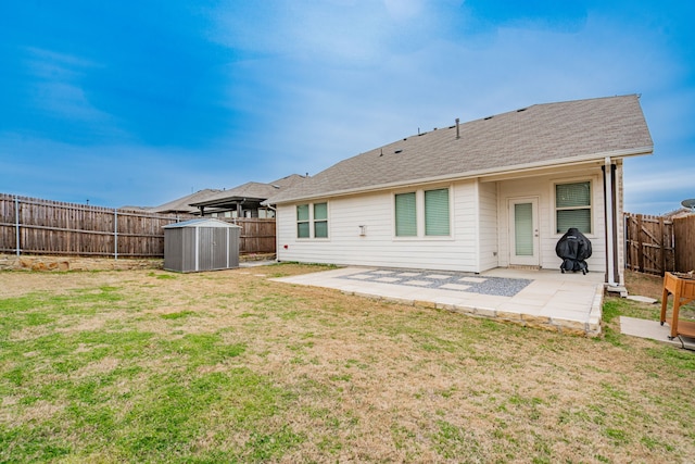 rear view of house featuring a patio, a shed, a yard, a fenced backyard, and an outdoor structure