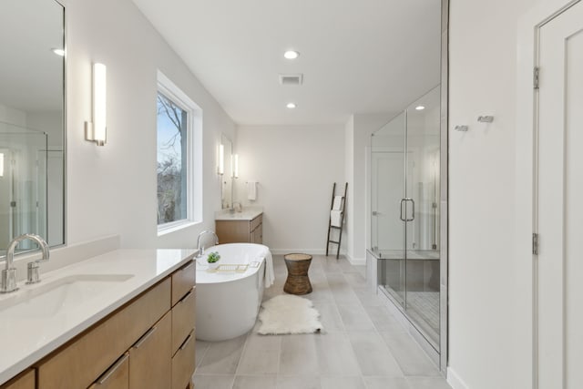 bathroom with a shower stall, a freestanding tub, visible vents, and a sink