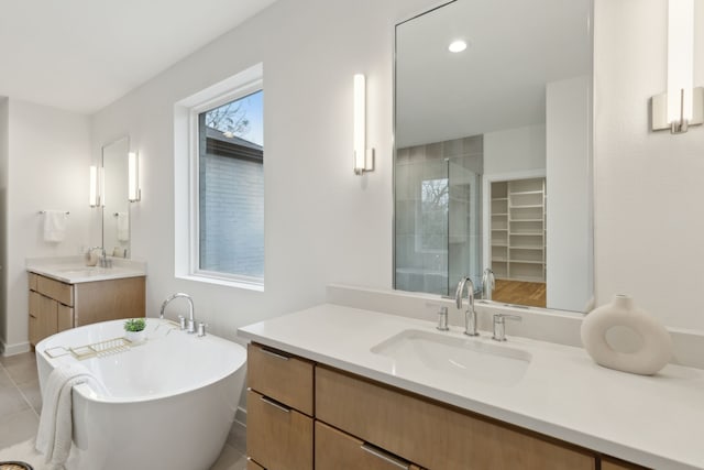 bathroom with a soaking tub, a shower stall, two vanities, and a sink