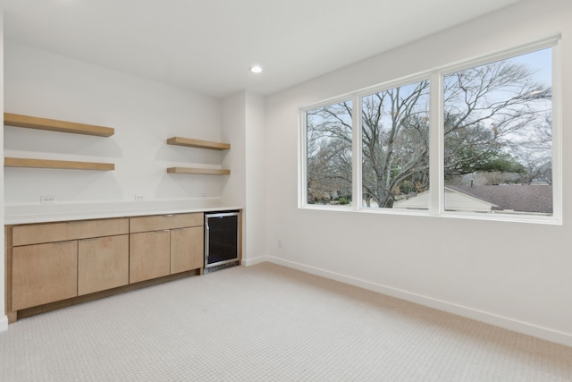 interior space featuring baseboards, recessed lighting, a bar, wine cooler, and light colored carpet