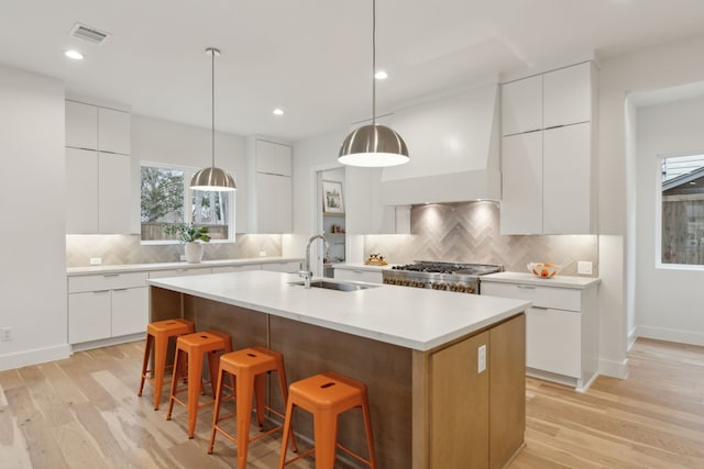 kitchen featuring visible vents, a breakfast bar, stove, modern cabinets, and a sink