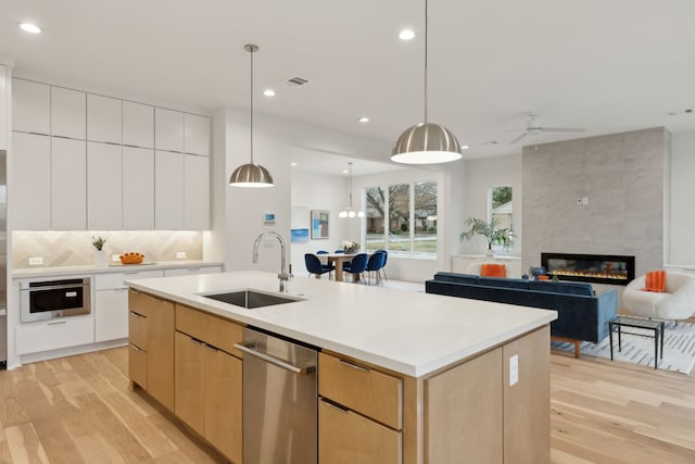 kitchen featuring visible vents, a tile fireplace, stainless steel appliances, modern cabinets, and a sink