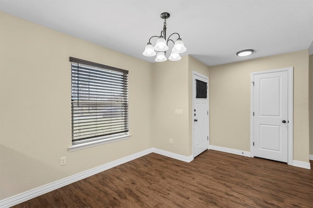 interior space featuring a chandelier, dark wood-type flooring, and baseboards