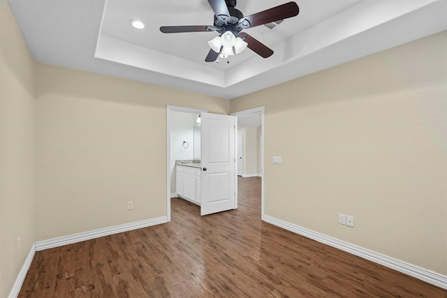 unfurnished bedroom with ceiling fan, baseboards, recessed lighting, wood finished floors, and a raised ceiling