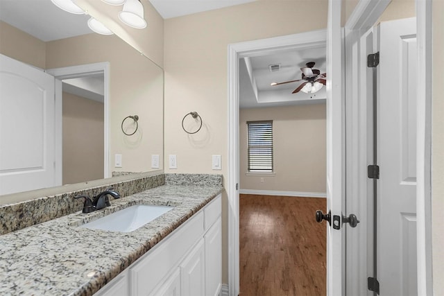 bathroom featuring visible vents, wood finished floors, vanity, a raised ceiling, and a ceiling fan