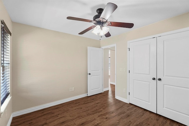 unfurnished bedroom with multiple windows, baseboards, a closet, and wood finished floors