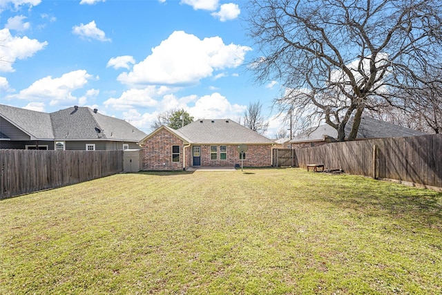 back of house with brick siding, a fenced backyard, and a lawn