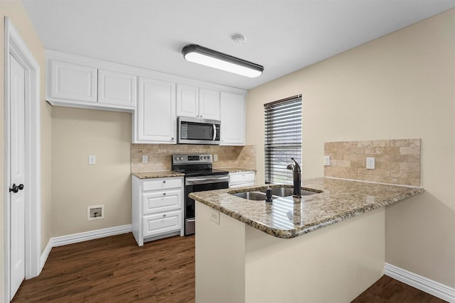 kitchen featuring light stone counters, a peninsula, a sink, stainless steel appliances, and dark wood-type flooring