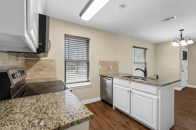 kitchen featuring visible vents, dark wood-type flooring, a peninsula, stainless steel appliances, and a sink