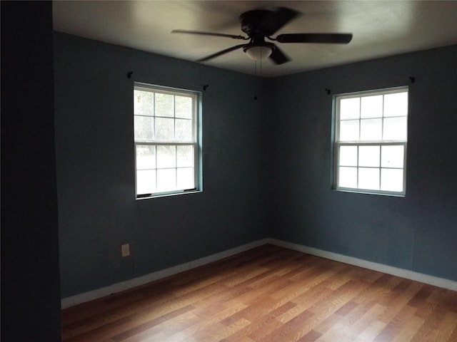 spare room with light wood-type flooring, baseboards, and a ceiling fan