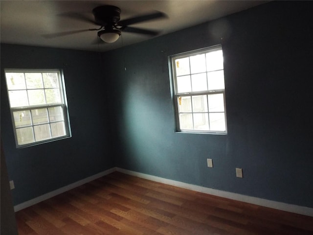 spare room featuring baseboards, dark wood-type flooring, and a ceiling fan