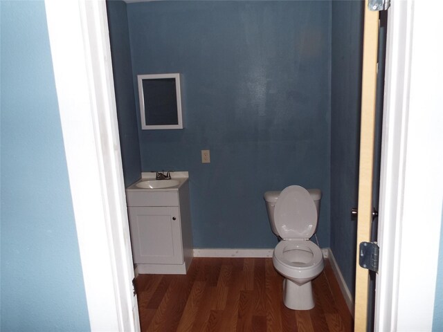 bathroom featuring toilet, vanity, baseboards, and wood finished floors