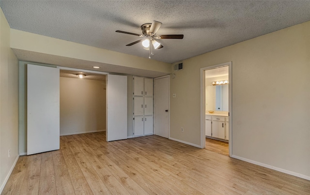 unfurnished bedroom featuring visible vents, baseboards, a textured ceiling, and light wood finished floors