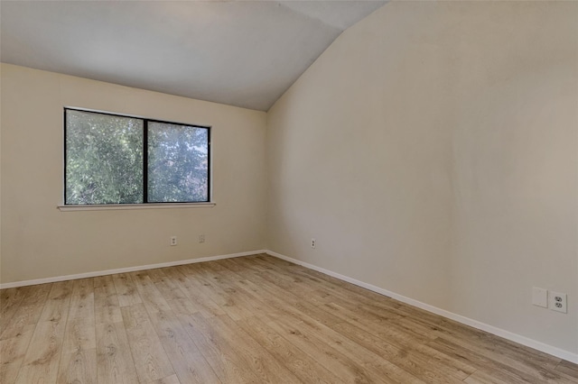 spare room with light wood-style flooring, baseboards, and vaulted ceiling