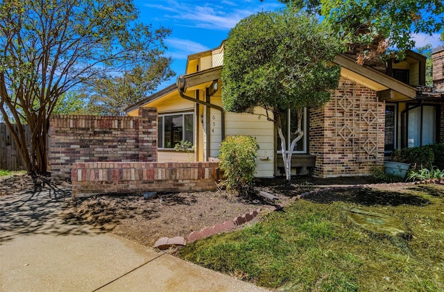 view of side of home featuring brick siding and fence