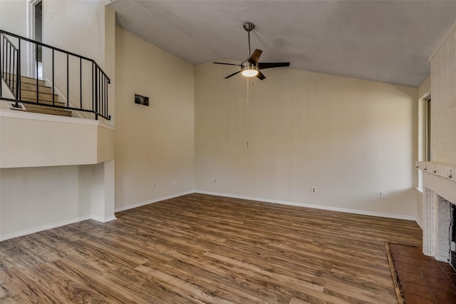 unfurnished living room with a brick fireplace, baseboards, ceiling fan, stairway, and wood finished floors